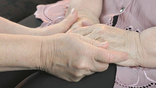 一个女人握着一个老妇人松弛的布满皱纹的手视频素材
