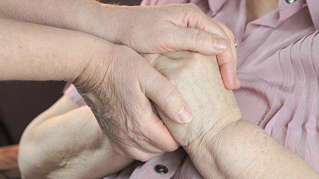 一个女人握着一个老妇人松弛的布满皱纹的手视频素材