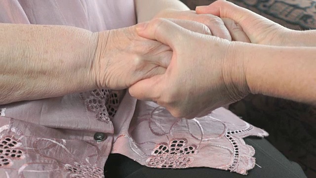 一个女人牵着一个年老女人松弛的布满皱纹的手视频素材