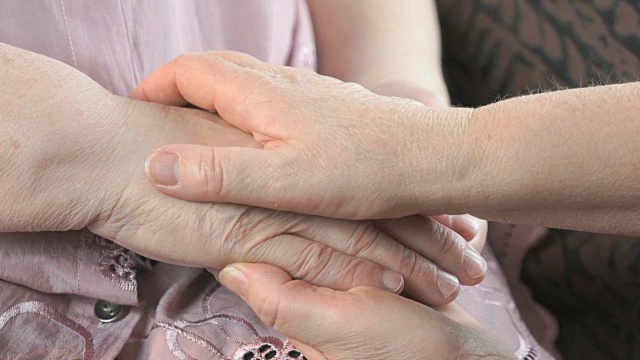 一个女人牵着一个年老女人松弛的布满皱纹的手视频素材