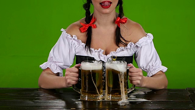 身着巴伐利亚服装的女孩倒啤酒。绿色的屏幕。慢动作视频素材