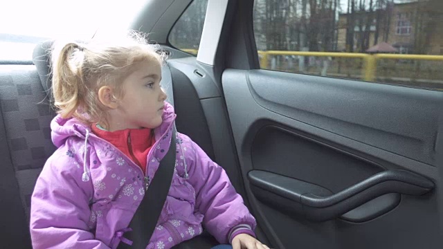 小女孩穿着暖和的衣服从车窗向外看。视频素材
