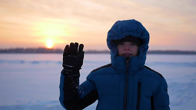 孩子挥手打招呼在冬季公园日落视频素材