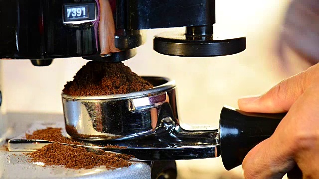 咖啡师从研磨机分配咖啡粉到门滤器。视频素材