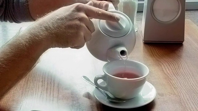男子从茶壶中倒茶并擦拭桌子视频下载