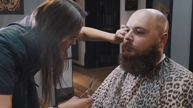 女理发师在理发店里用剪刀修剪顾客的胡子视频素材