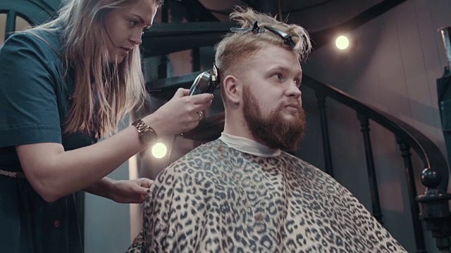 一名女理发师在理发店里用剪子给顾客理发视频素材
