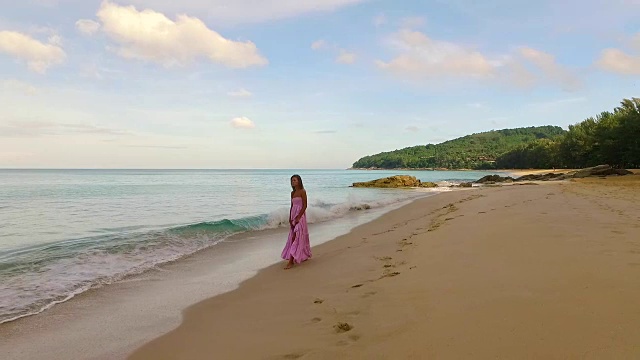 空中:孤独的女孩走在海边靠近海浪。视频素材