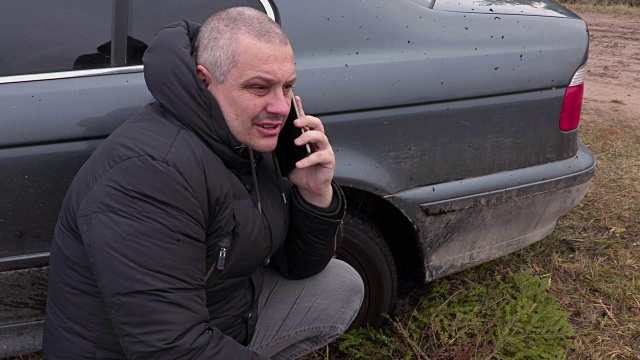 一名男子在被困在泥里的汽车附近打电话视频下载