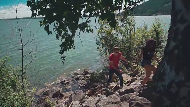 一对迷人的情侣在岩石海岸散步视频素材