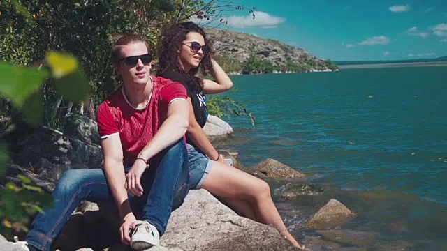 一对迷人的夫妇坐在岩石海岸上视频素材