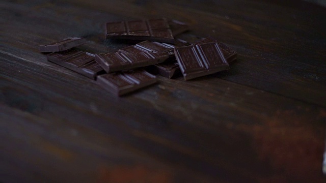 木桌上的玻璃黑巧克力棒和可可粉。切碎的巧克力视频素材