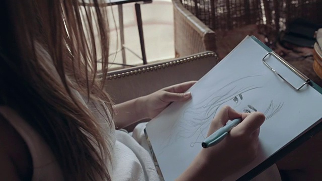 年轻女子在咖啡馆用铅笔画肖像视频下载