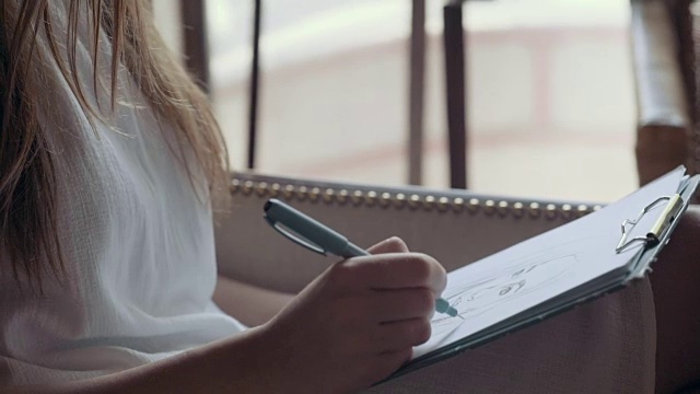 年轻女子在咖啡馆用铅笔画肖像视频下载