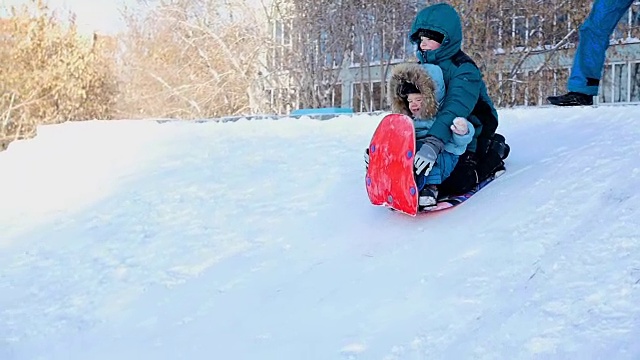 孩子们一起用雪橇从山上滚下来视频素材