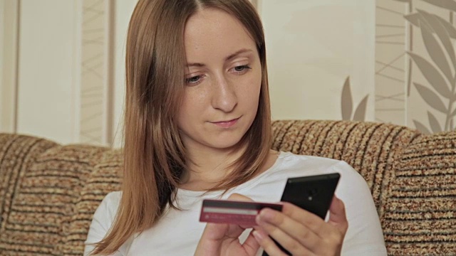 年轻的白人女性用智能手机在网上购物视频下载