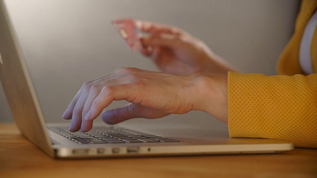 女人的手拿着信用卡，用电脑键盘进行网上购物视频下载