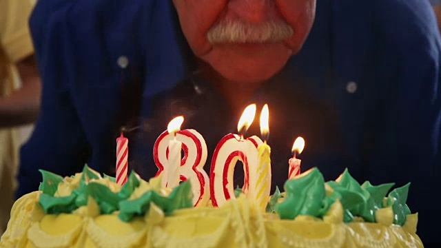 蛋糕和老人吹蜡烛在生日派对视频素材