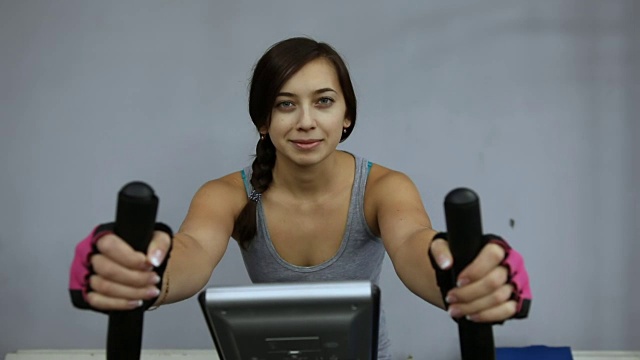 女孩在健身房里骑着健身自行车训练视频下载