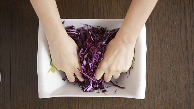 女用手揉成一团的红卷心菜沙拉。视频素材