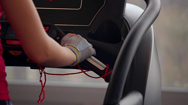 在健身房里的跑步机上行走。在运动设备上戴手套的女人的手的特写。在体育俱乐部锻炼视频素材