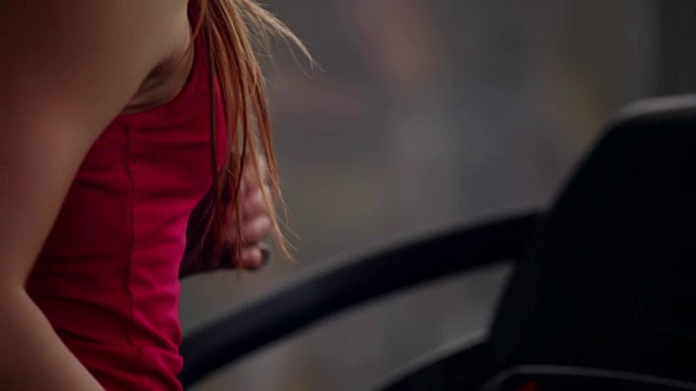 一个女人在跑步机上跑步的背影和侧视图，同时在一个体育俱乐部。在健身房训练视频素材