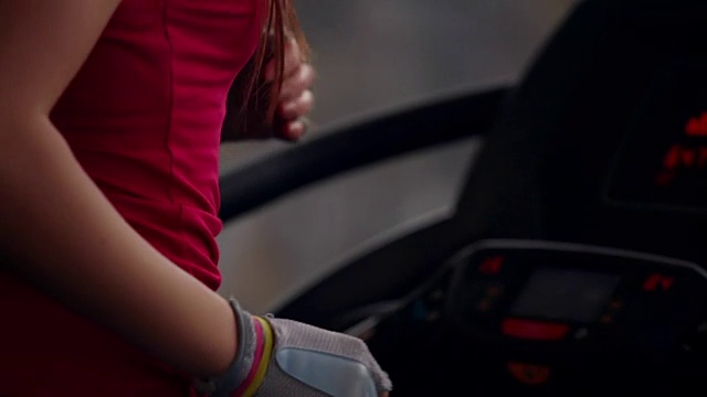 背部和侧面的观点，一个深色头发的女人跑在跑步机上，而在一个体育俱乐部。替身拍摄视频素材
