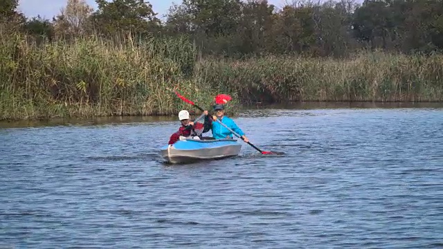 女孩们在森林河上的皮划艇里游泳视频素材