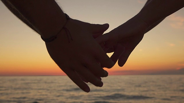 慢动作，特写:爱的男孩和顽皮的女人牵手在海洋海滩视频素材
