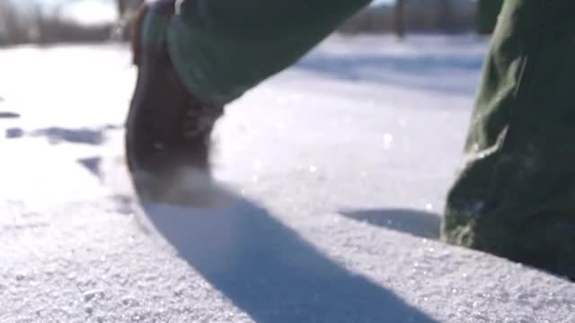 一个人的脚在雪山上行走的特写。慢动作拍摄视频素材