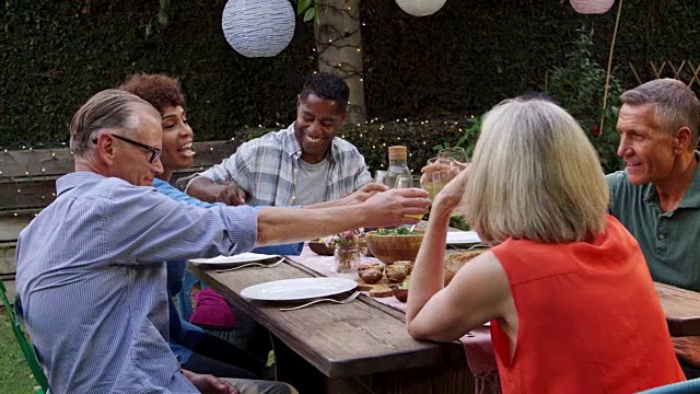 成熟的朋友享受户外餐在后院拍摄R3D视频素材