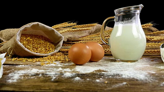 小麦，面粉，面包，牛奶，鸡蛋和黄油放在一张木桌上视频素材