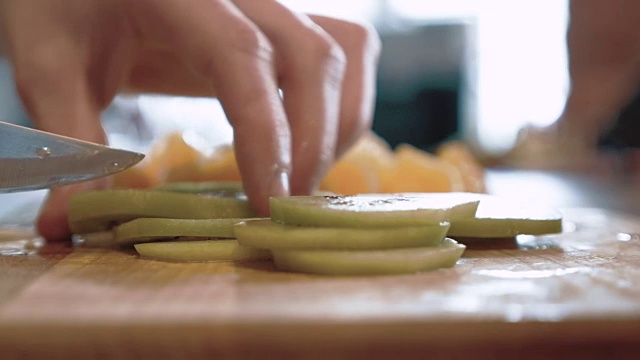 一位厨师将切好的猕猴桃和橙子放在砧板上，慢动作视频素材