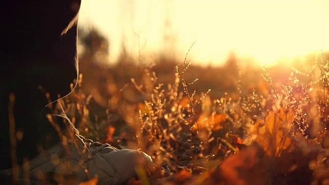 一个人在秋天公园的黄叶上慢镜头地走着。男人的脚步。近距离视频素材
