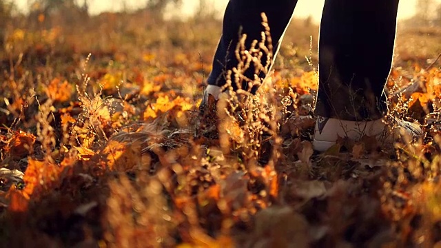 一个人在秋天公园的黄叶上慢镜头地走着。男人的脚步。近距离视频素材