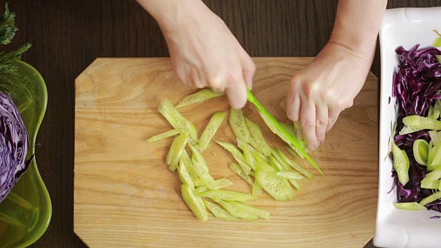 女人的手用刀切红卷心菜沙拉。切黄瓜视频素材