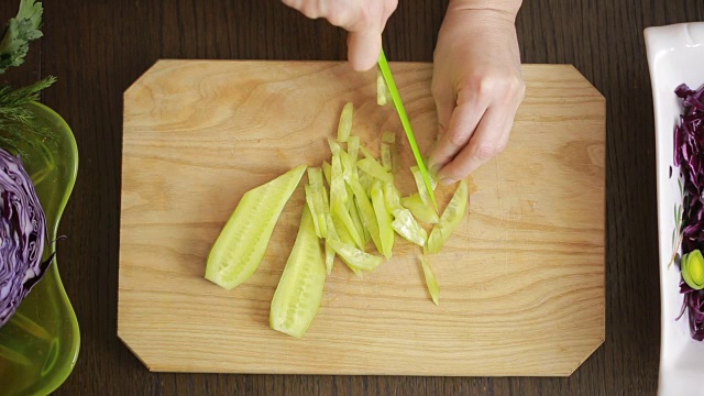 女人的手用刀切红卷心菜沙拉。切黄瓜视频素材