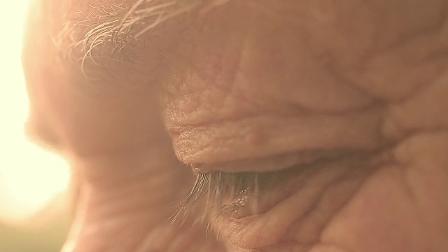 特写照片上的眼睛老人与太阳背光:看，皱纹的人视频素材