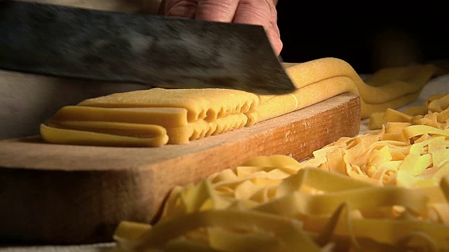自制新鲜意大利面:在木桌上用传统刀切意大利面视频素材