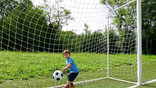 一个小男孩在足球场上进球的跟踪摄像机视频素材
