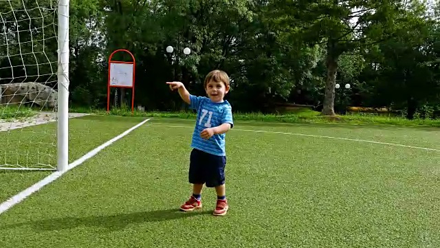 一个小男孩在足球场上进球的跟踪摄像机视频素材