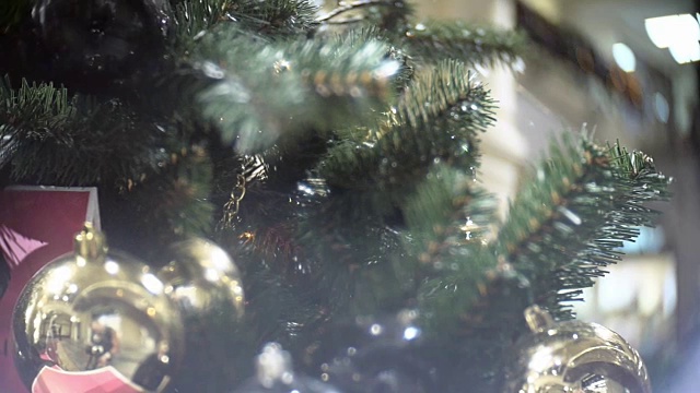 滑出金色的磨砂和镜子球。新年和抽象模糊的购物中心背景与圣诞树装饰视频素材