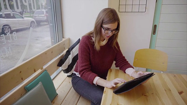 可爱的年轻女学生在咖啡馆用平板电脑视频素材
