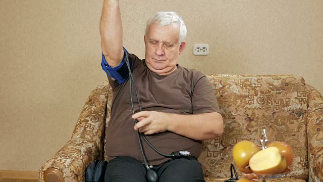 男人上了年纪，体重超标，自己在家躺椅上测量压力。他通过血压计听脉搏视频下载