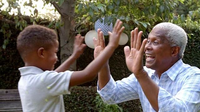 小黑人男孩和爷爷在花园里玩拍手游戏视频素材
