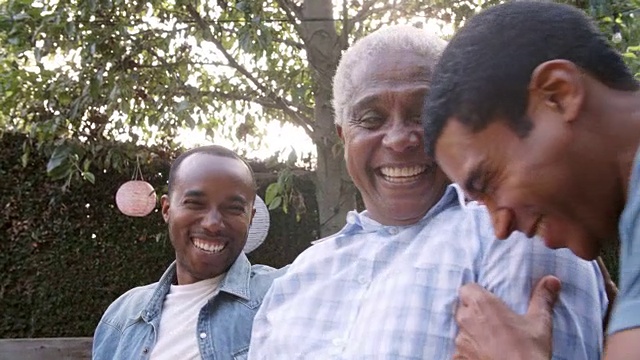 黑人爸爸和两个成年的儿子在花园里一起笑视频素材