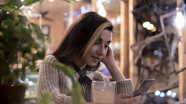 在时尚的都市咖啡馆里喝着咖啡，用智能手机应用发短信。视频素材