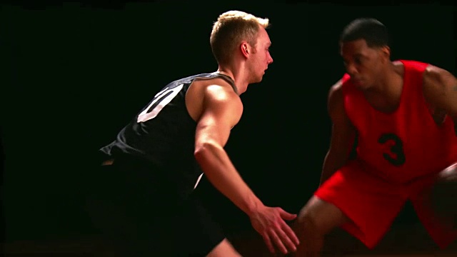 篮球运动员在近距离对抗一个黑色背景的对手视频下载