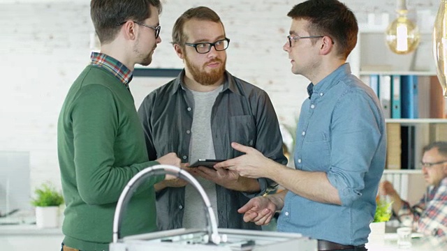 三个有创意的人互相传递平板电脑讨论业务事宜。人们在后台工作。视频素材