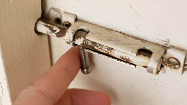 一个人打开一个旧的滑动锁，打开一扇门。视频下载